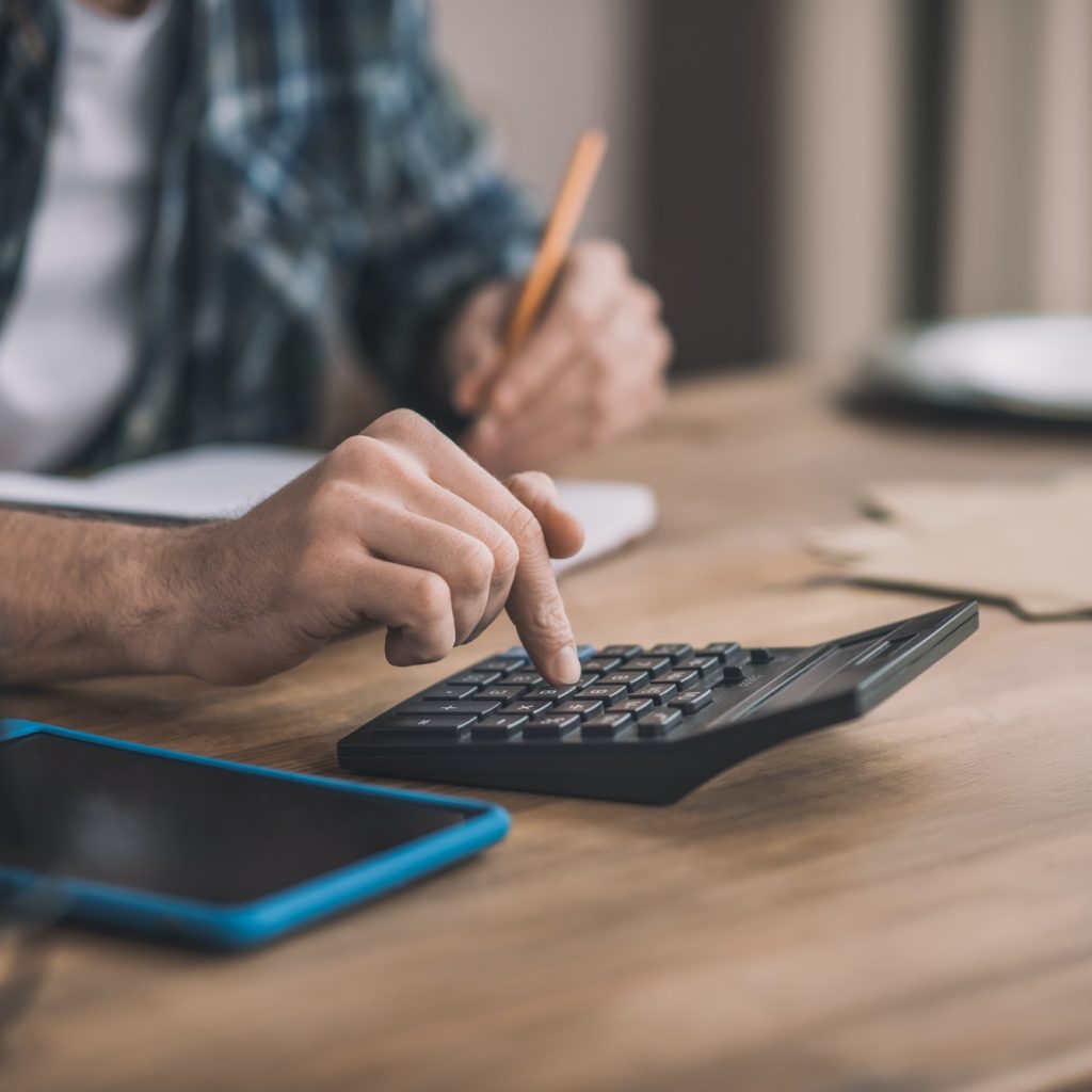 Man using a calc and other gadgets for financial estimation