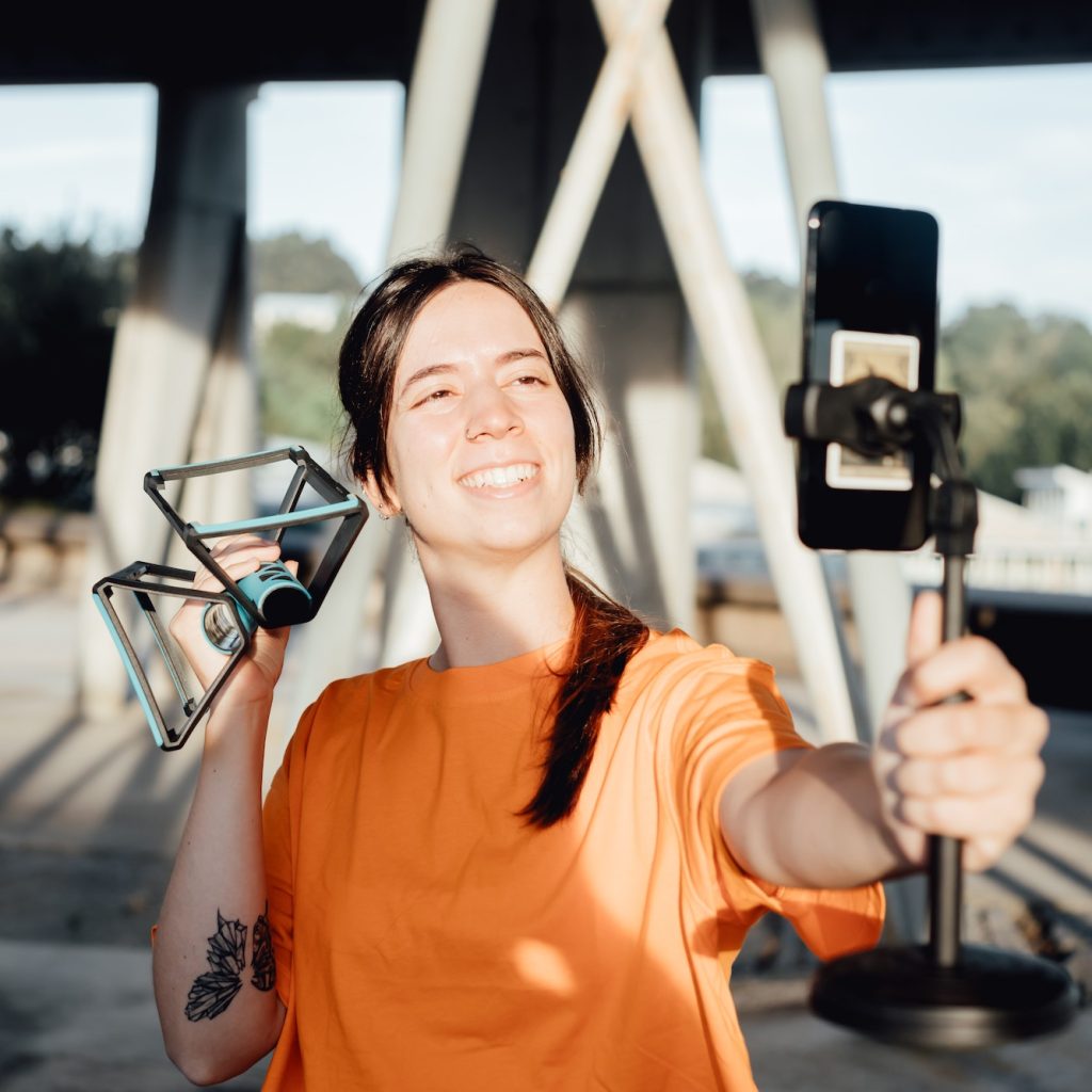 Woman holding push ups bar cross smiling at mobile phone describing the details,specifications and f